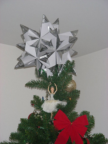一颗用银色锡箔纸制作的模块化折纸星，展示了许多折叠单元如何拼合在一起