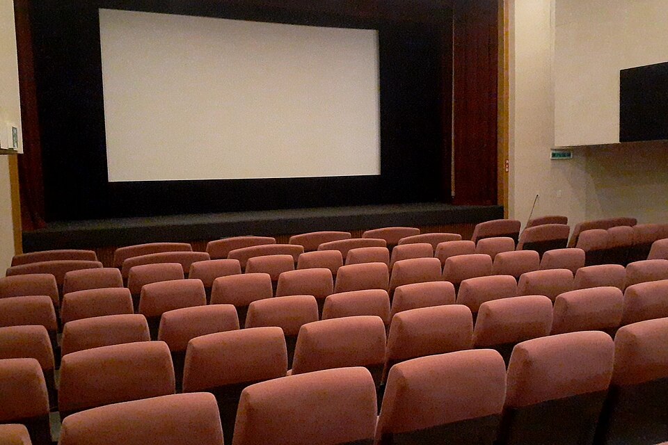 El interior de un cine con filas de asientos frente a una gran pantalla