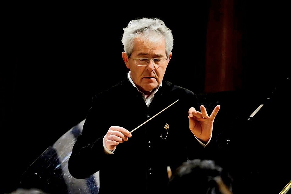 An orchestra conductor holding a baton while leading a performance