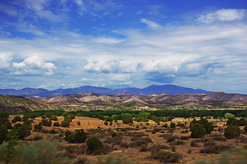 A desert landscape in New Mexico with red cliffs and blue sky, the kind of scenery Georgia O’Keeffe loved to paint