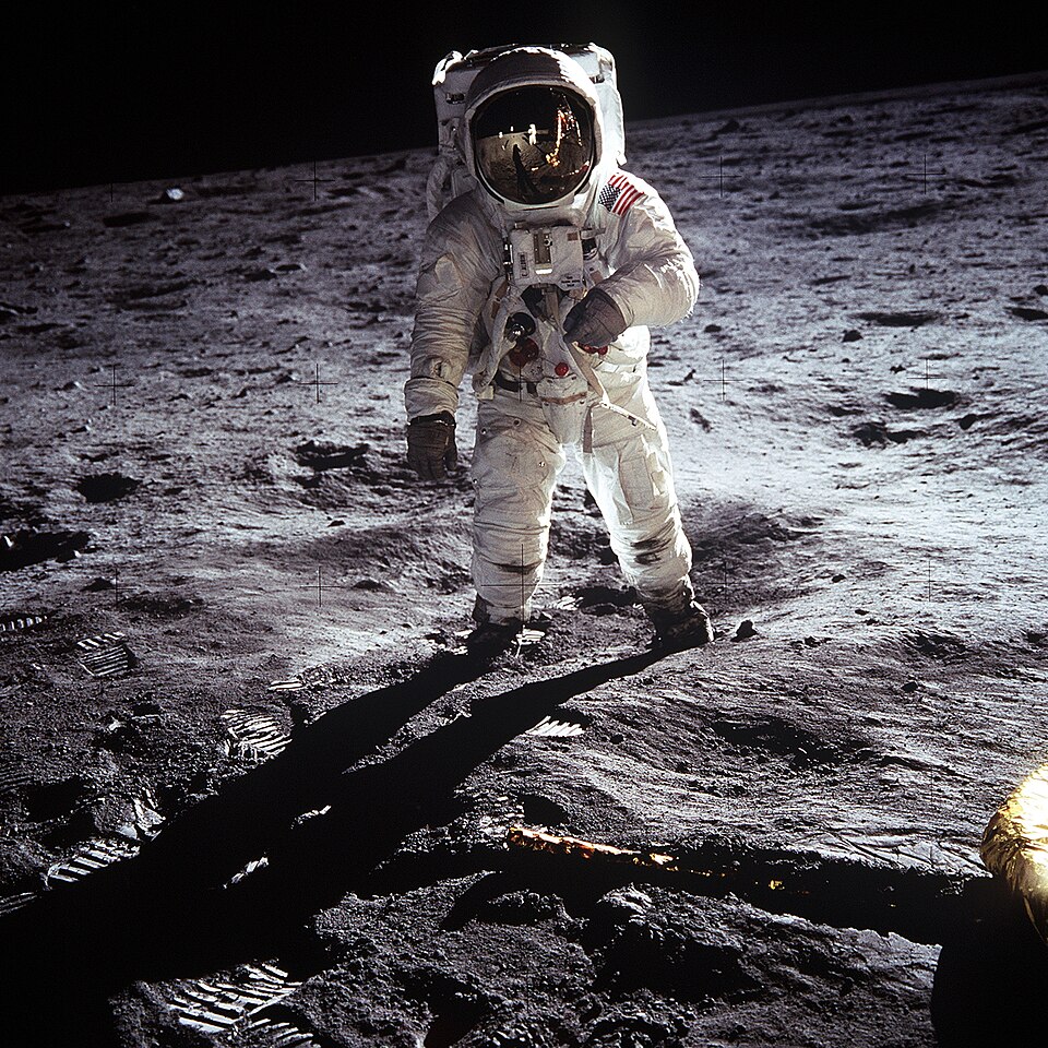 Buzz Aldrin standing on the Moon in his white spacesuit with the lunar module behind him