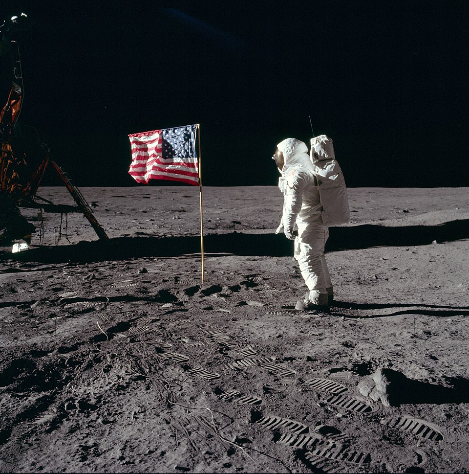 Neil Armstrong standing on the Moon next to the American flag