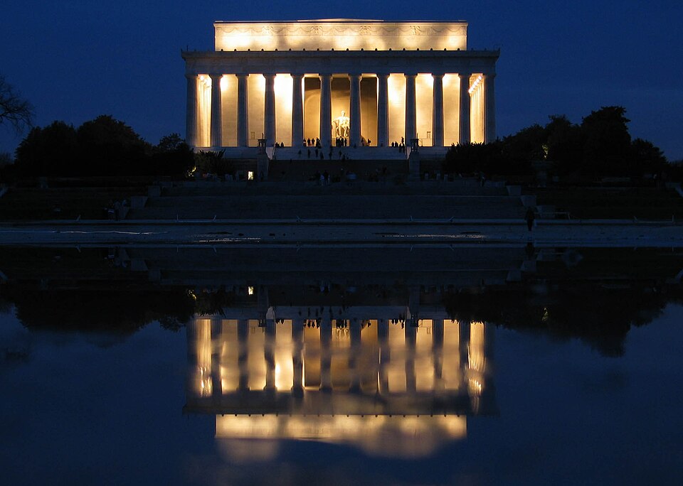 The Lincoln Memorial at night with its columns lit up and reflected in the water