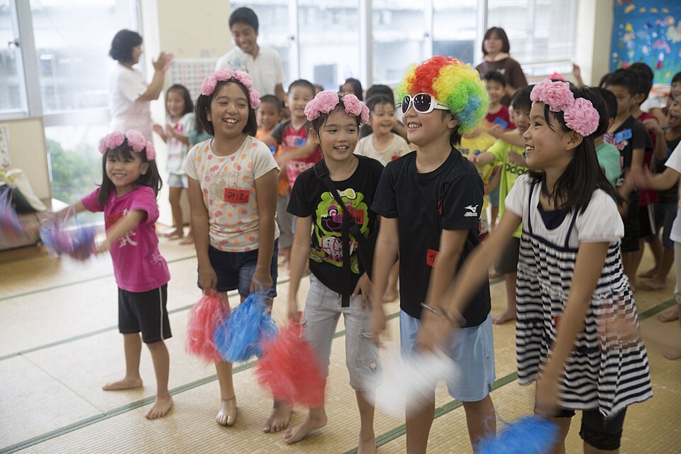 Children smiling and dancing together with colorful pom-poms