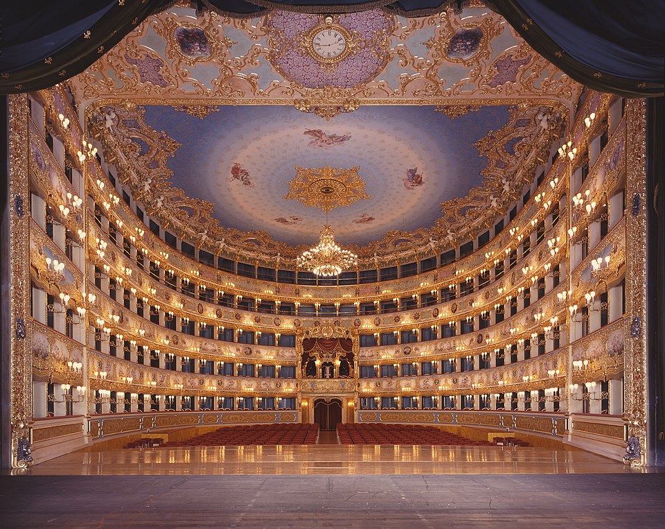 The inside of a grand theater with rows of balconies and a beautiful painted ceiling
