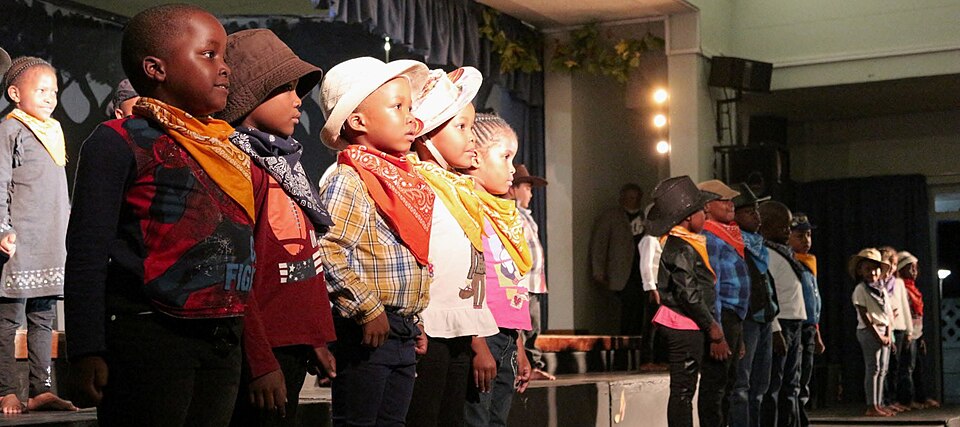 Niños con disfraces actuando en el escenario durante una obra escolar