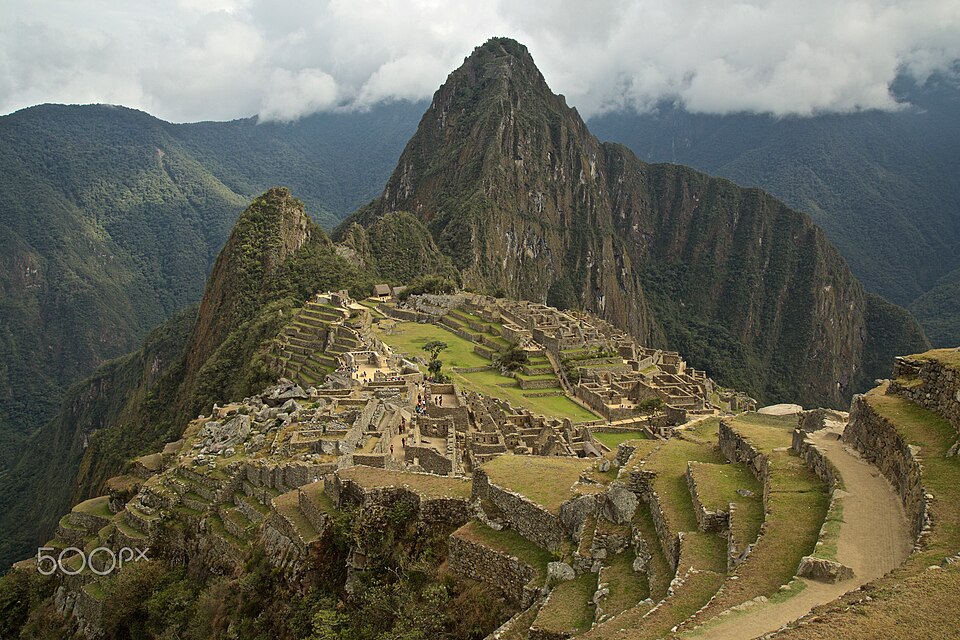 Las ruinas de piedra de Machu Picchu con montañas verdes y nubes detrás