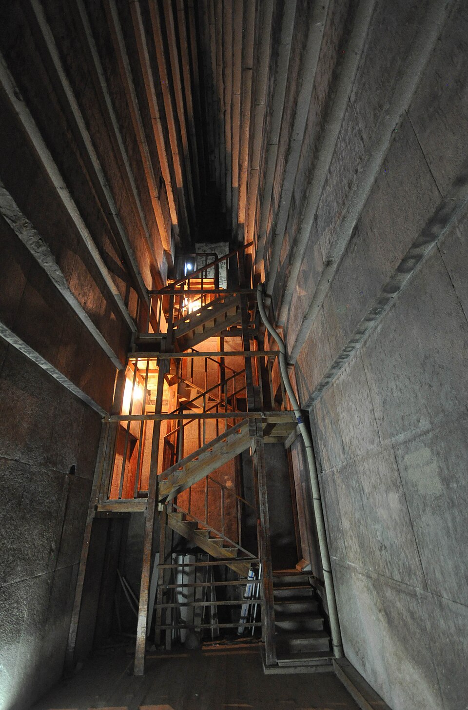 Inside the tall chamber of an Egyptian pyramid with stone walls rising high above