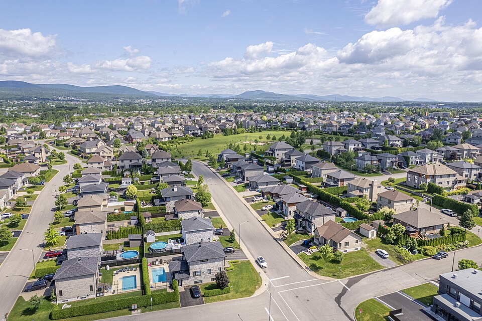 Vista aérea de un barrio residencial con muchas casas unifamiliares, jardines verdes y calles sinuosas